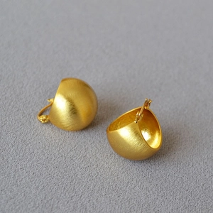 Detailed view of gold-plated bean earrings featuring a brushed metallic finish