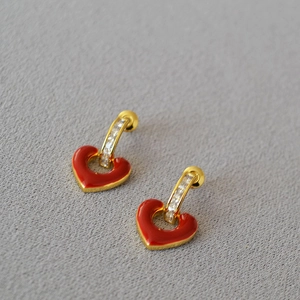 Detail of red enamel heart earrings with gold plating and sparkling zircon stones