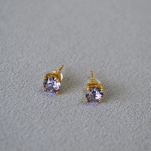 Detailed macro view of lavender round crystal stud earrings with gold four-prong setting