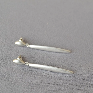 Detailed macro view of minimalist silver brass earrings with a brushed matte texture finish
