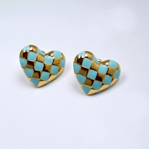 Detail view of heart-shaped checkered earrings with gold plating and blue enamel finish
