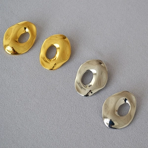 Detailed view of irregular molten metal stud earrings in gold and silver finishes