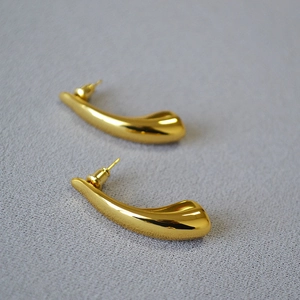 Close-up of gold-plated horn-shaped teardrop earrings with a polished mirror finish