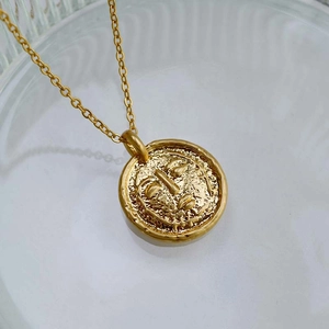 Gros plan du pendentif plaqué or avec visage en relief sur surface en verre