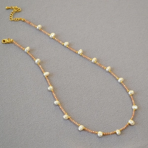 Macro view of freshwater pearl petal beaded necklace with gold lobster clasp and extension chain