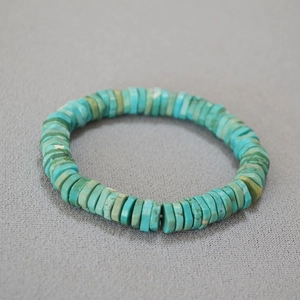 Detailed view of turquoise disc beads with natural textures on a beaded stretch bracelet