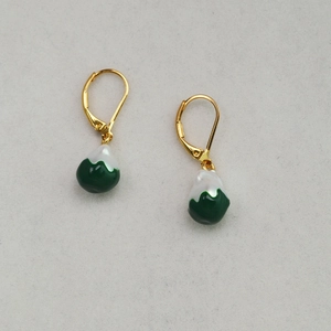 Detail of green and white teardrop earrings with gold leverback hooks on grey surface