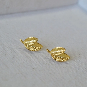Macro shot of gold leaf earrings showing intricate hammered metal texture and layered design