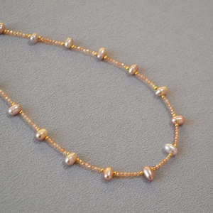 Macro shot of freshwater pearl necklace with orange crystal beads and gold spacers
