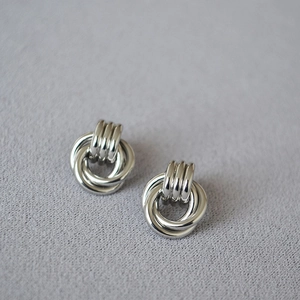 Detail of minimalist silver-plated brass earrings with overlapping layered hoop design