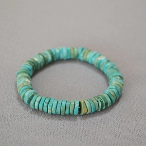 Close-up of vintage irregular turquoise heishi bead bracelet on textured background