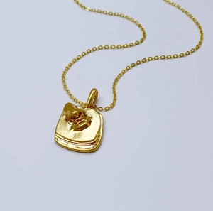 Vue détaillée d'un collier en laiton doré avec un pendentif à motif de relief carré