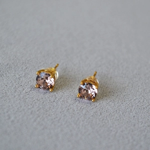 Macro detail of champagne crystal earrings with gold four-prong setting and silicone backings