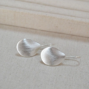Detailed view of silver leaf earrings featuring a minimalist brushed metal texture finish