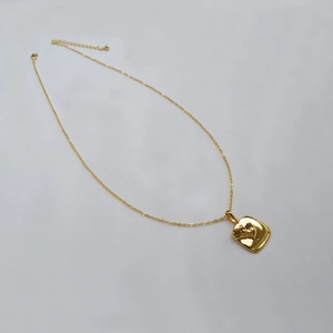 Détail d'un collier plaqué or minimaliste avec un pendentif texturé organique