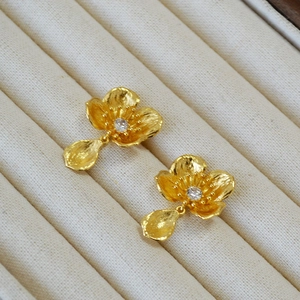 Detailed macro view of vintage gold flower earrings with a zircon center and petal drop