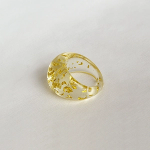Détail de la bague en résine transparente ornée de feuilles d'or pour femme