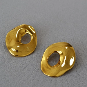 Detailed view of irregular wavy golden hoop earrings with a polished mirror finish