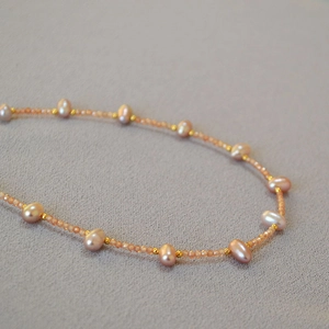 Macro detail of freshwater rice pearls with orange crystals and gold spacer beads