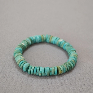 Retro elastic bracelet featuring irregular turquoise heishi beads on a grey background