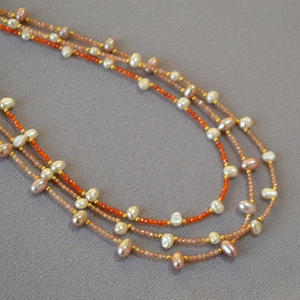 Macro shot of multi-layer freshwater pearl necklace with colorful beads and gold metal spacers