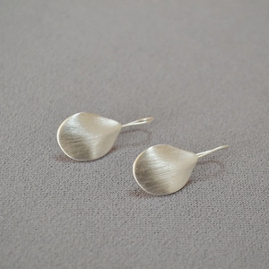Macro shot of silver-toned leaf-shaped earrings with a brushed metal texture finish