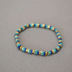 Detail of bohemian turquoise Heishi bead bracelet with marble patterns and gold accents