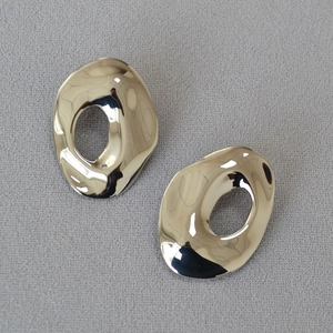 Macro detail of high-polish irregular oval hollow gold-plated brass earring