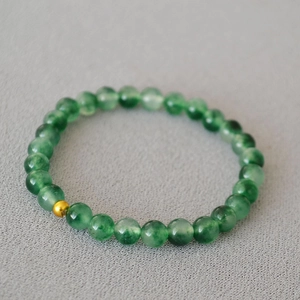 Détail d'un bracelet minimaliste en perles de pierres vertes avec une perle dorée