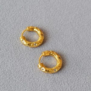 Orecchini a cerchio vintage in oro martellato con zirconi brillanti su fondo grigio