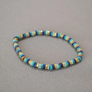 Detail of bohemian turquoise Heishi bead bracelet with golden accents and flat disk shapes