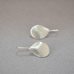 Macro shot of silver irregular leaf earrings with a brushed metallic texture finish