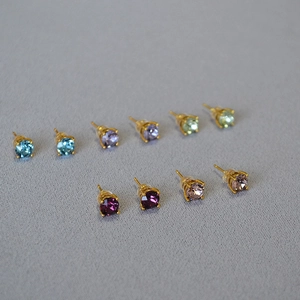 Detail of 5 pairs of colorful crystal stud earrings with 925 silver needles on gray fabric