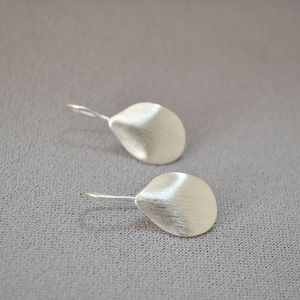 Detailed close-up of silver leaf earrings with a delicate brushed metal texture and matte finish