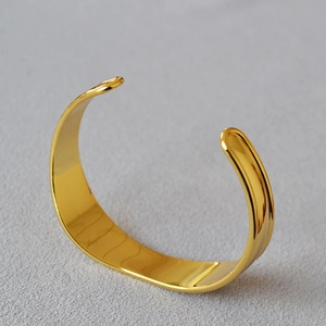 Macro detail of polished irregular gold-plated brass cuff bracelet with glossy finish