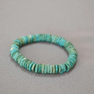 Close-up of flat rectangular turquoise stone beads with natural texture on a beaded bracelet