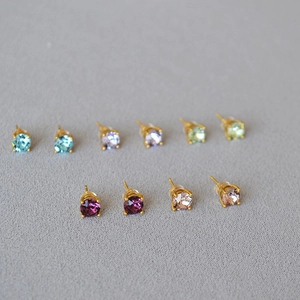 Macro view of crystal stud earrings in five colors with golden four-prong settings