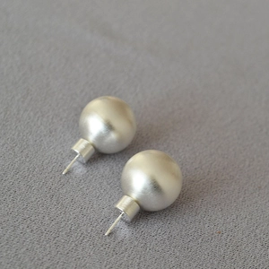 Vue détaillée des boucles d'oreilles boules argentées avec texture métal brossé