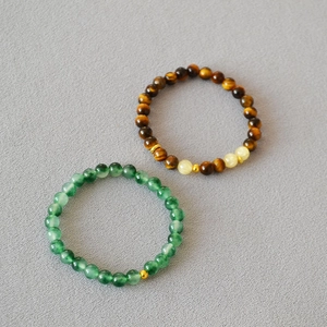 Gros plan de perles en oeil de tigre et bracelets en jade vert avec accents métalliques
