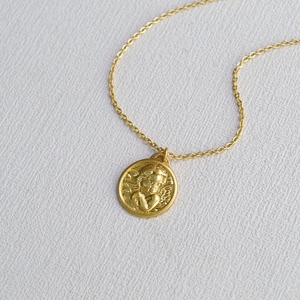 Vue macro détaillée d'un pendentif ange en relief en laiton doré sur une chaîne fine