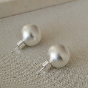 Vue détaillée des boucles d'oreilles sphères en métal brossé mat avec texture minimaliste