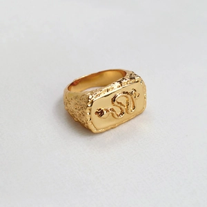 Gros plan d'une bague en laiton doré avec relief serpent et texture martelée