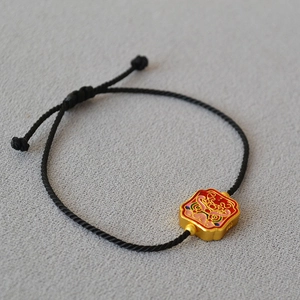 Detail of vintage brass bracelet with colorful enamel charm and black braided rope
