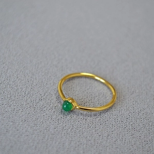 Close-up of gold plated brass ring featuring a green gemstone in a bezel setting