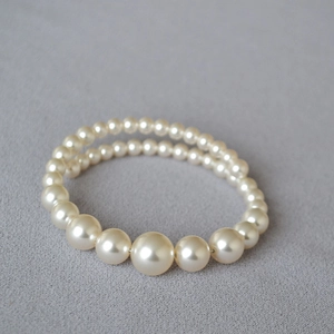 Detail of double-layer faux pearl bracelet with gradient bead sizes on grey fabric