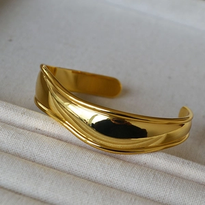 Detailed macro shot of a gold-plated irregular wavy cuff with high mirror polish finish