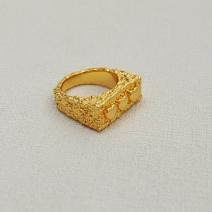 Vue détaillée d'une bague en laiton doré avec texture lave et trois motifs de cœur