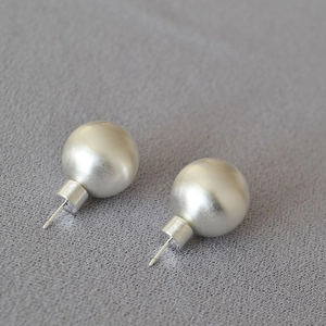 Vue détaillée de boucles d'oreilles boules en argent brossé mat sur tissu texturé