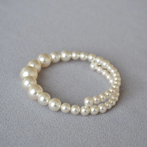 Detail of layered wrap bracelet featuring cream gradient faux pearls on grey fabric