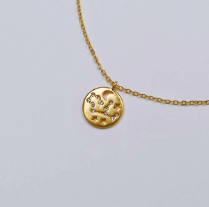Détail macro du pendentif zodiaque plaqué or avec zircons et motifs d'étoiles évidés
